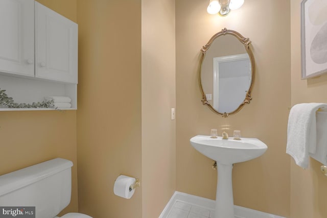 half bathroom with tile patterned floors, toilet, and baseboards