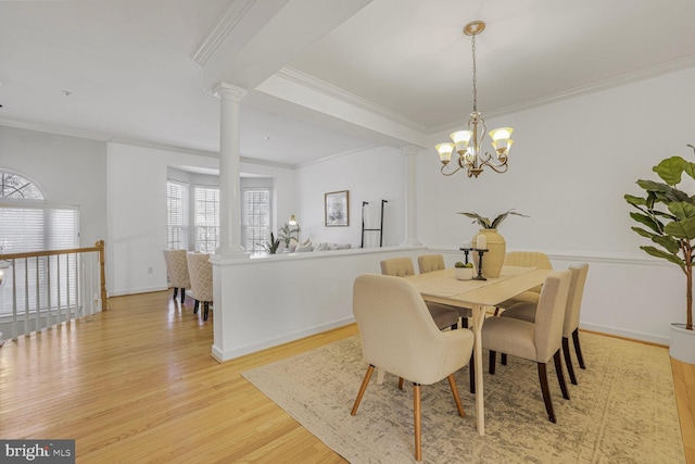 dining area featuring crown molding, decorative columns, and light wood finished floors