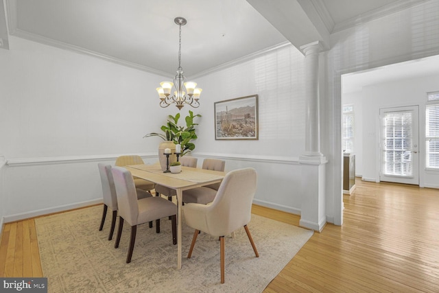 dining room with light wood finished floors, a chandelier, decorative columns, and ornamental molding