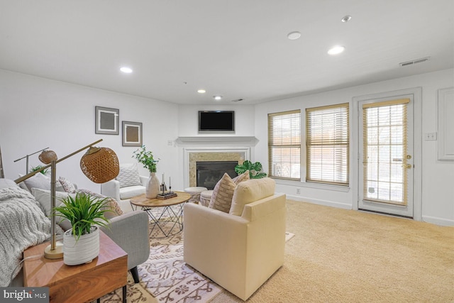 living area with visible vents, baseboards, recessed lighting, a glass covered fireplace, and light colored carpet