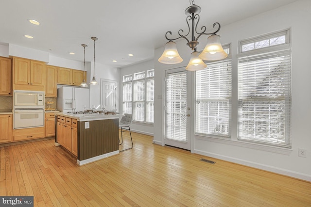 kitchen with light wood finished floors, visible vents, backsplash, light countertops, and white appliances