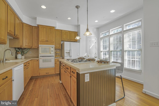 kitchen with white appliances, light countertops, light wood-type flooring, and a sink