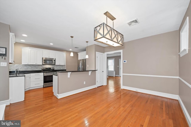 kitchen with backsplash, stainless steel appliances, dark countertops, and visible vents