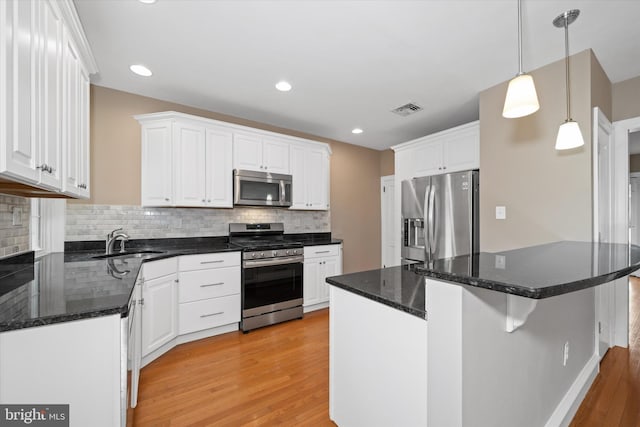 kitchen featuring visible vents, white cabinetry, stainless steel appliances, and a sink