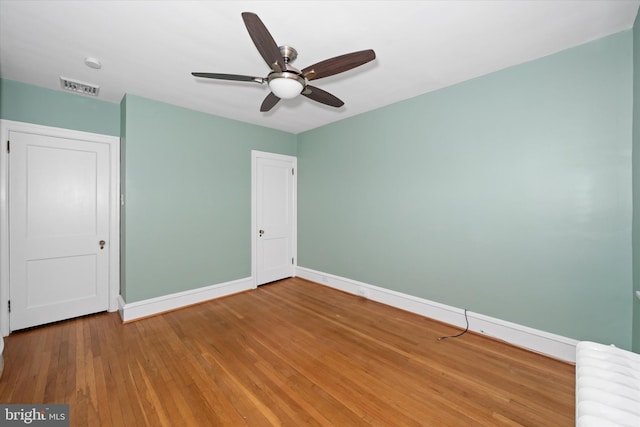 unfurnished bedroom with a ceiling fan, baseboards, visible vents, and wood-type flooring