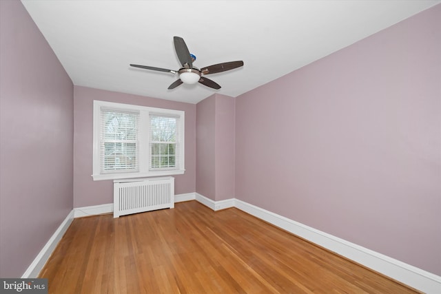 empty room with light wood-style flooring, radiator, baseboards, and ceiling fan