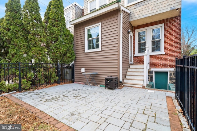 back of house featuring a patio, brick siding, and fence