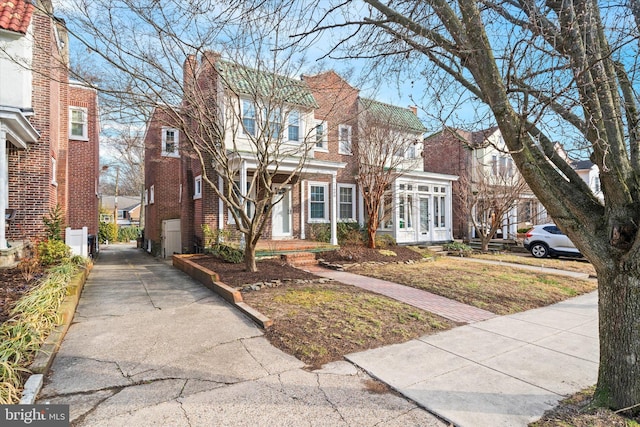 view of front facade featuring brick siding, french doors, and a chimney