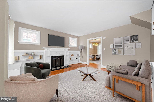 living area with a fireplace with flush hearth, baseboards, and wood finished floors