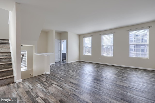 unfurnished living room with baseboards, wood finished floors, and stairs