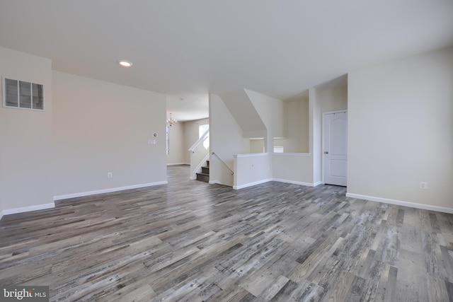 unfurnished living room with visible vents, wood finished floors, recessed lighting, an inviting chandelier, and baseboards