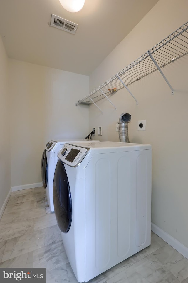 laundry room featuring washing machine and clothes dryer, visible vents, baseboards, laundry area, and marble finish floor