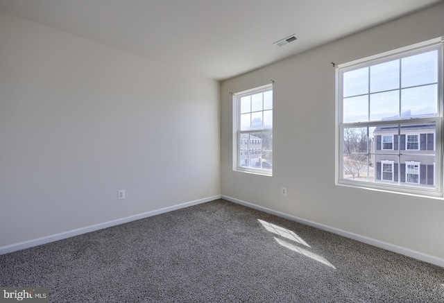 carpeted spare room featuring visible vents and baseboards