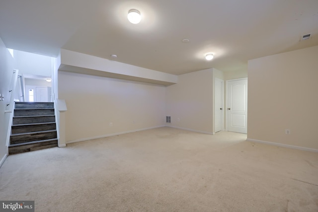 finished below grade area with stairway, light carpet, baseboards, and visible vents