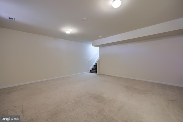 finished basement with visible vents, baseboards, light colored carpet, and stairs