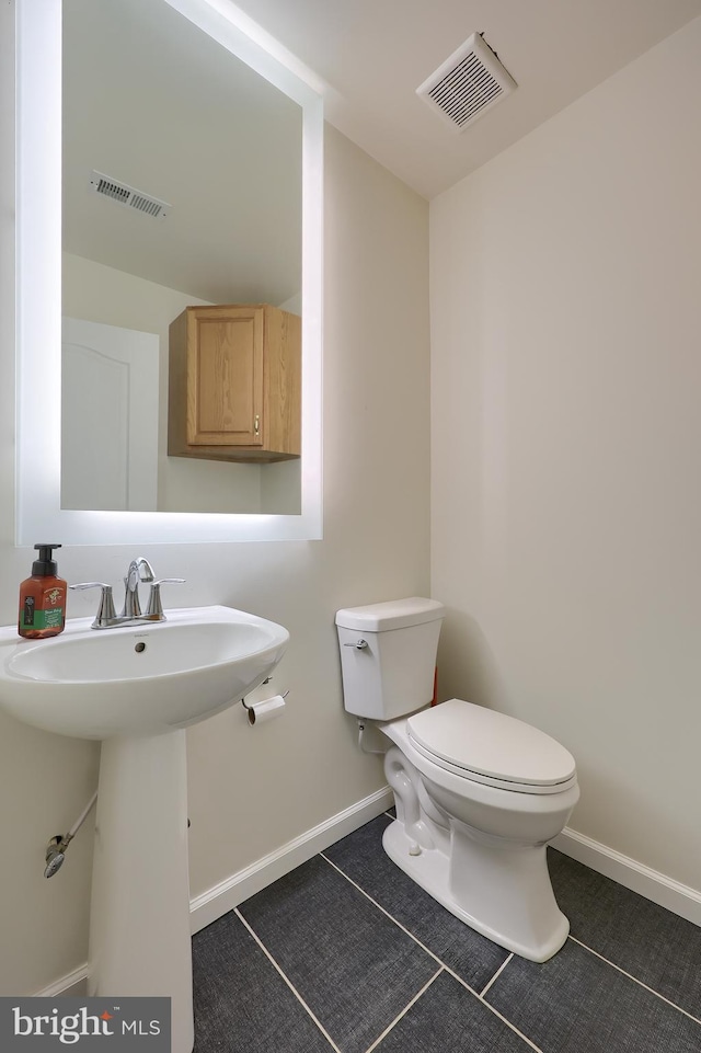 bathroom featuring toilet, baseboards, visible vents, and a sink