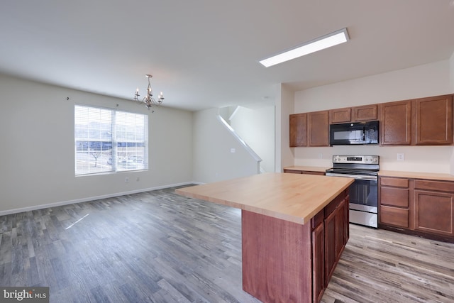 kitchen with light wood finished floors, a kitchen island, an inviting chandelier, stainless steel electric range, and black microwave