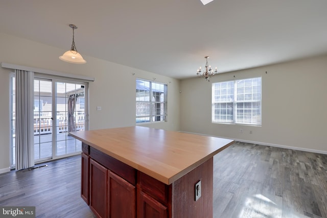 kitchen with a chandelier, a kitchen island, pendant lighting, and wood finished floors