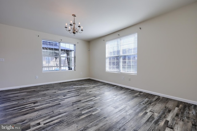 empty room featuring baseboards, a chandelier, and dark wood finished floors