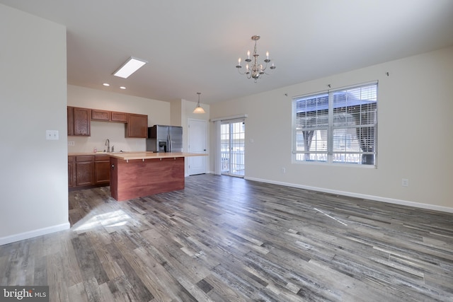 kitchen featuring a kitchen island, baseboards, stainless steel fridge with ice dispenser, light countertops, and dark wood-style floors