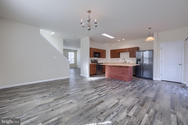 kitchen featuring wood finished floors, appliances with stainless steel finishes, open floor plan, and light countertops