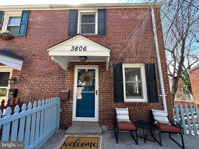 entrance to property featuring brick siding and fence