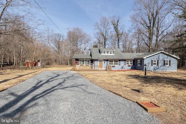 view of front of property featuring roof with shingles, a porch, and driveway