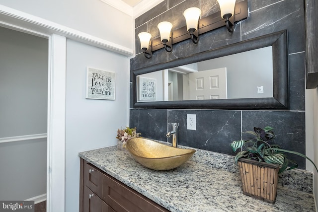 bathroom featuring backsplash, ornamental molding, and vanity