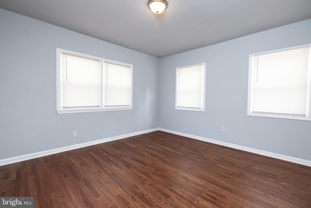 empty room with baseboards and dark wood-type flooring