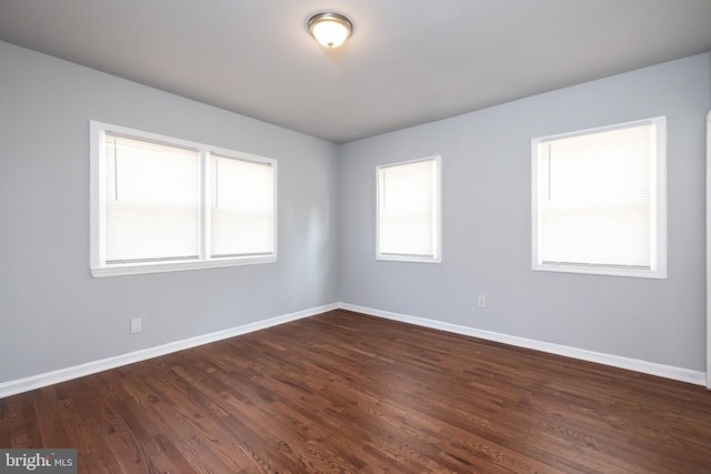 empty room featuring baseboards and dark wood-style flooring