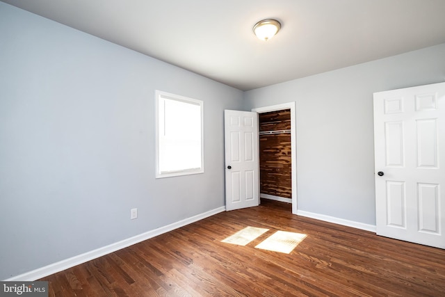 unfurnished bedroom with a closet, baseboards, and wood finished floors