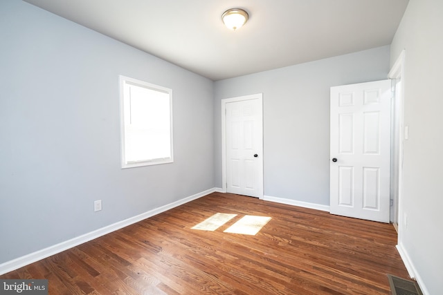 unfurnished bedroom with visible vents, baseboards, and wood finished floors