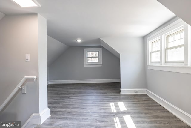 additional living space with baseboards, wood finished floors, and vaulted ceiling