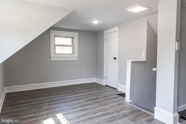 additional living space featuring baseboards and wood finished floors