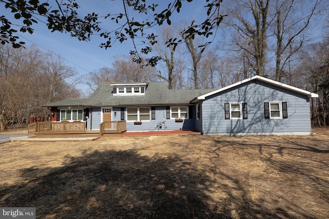 rear view of property with a wooden deck and roof with shingles