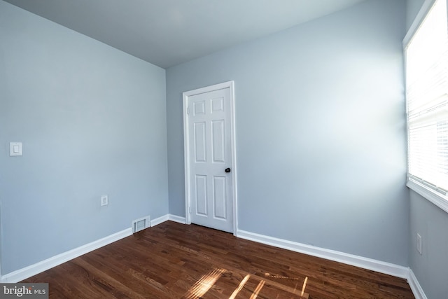 empty room with baseboards, dark wood finished floors, and visible vents