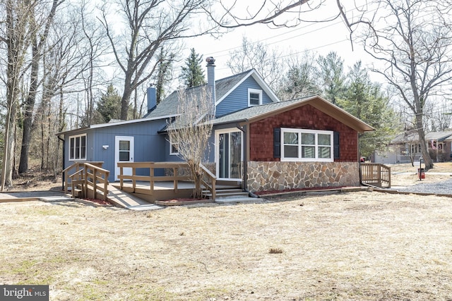 view of front of property featuring stone siding, roof with shingles, and a deck