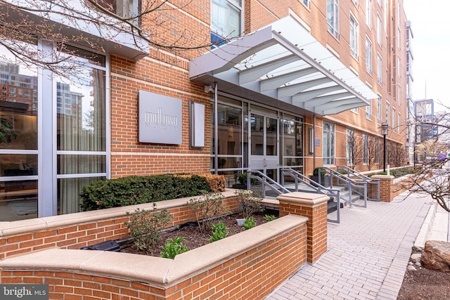 property entrance with brick siding and a patio area