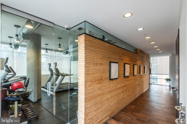 hall featuring a wall of windows, plenty of natural light, wood finished floors, and recessed lighting