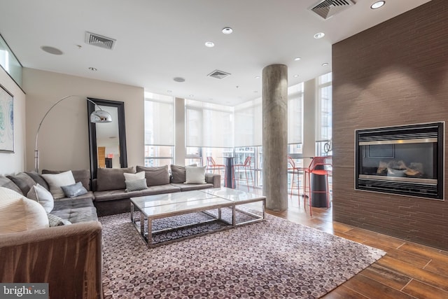 living area with wood finish floors, visible vents, and expansive windows