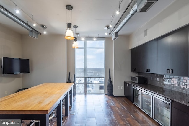 kitchen with visible vents, wooden counters, rail lighting, stainless steel microwave, and backsplash