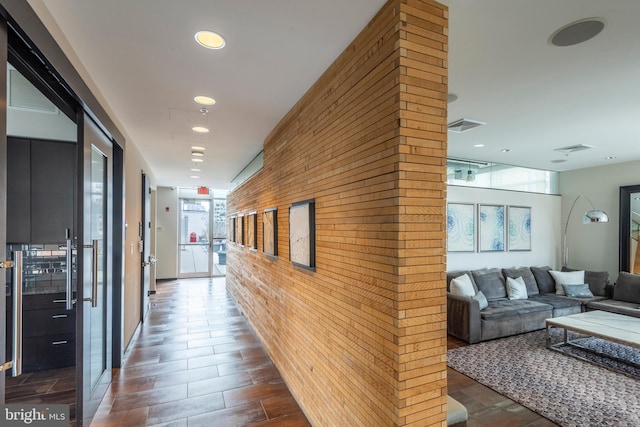 hallway featuring recessed lighting, visible vents, brick wall, and wood tiled floor