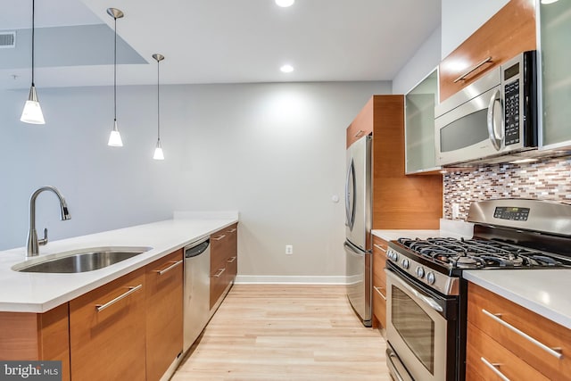 kitchen with a sink, appliances with stainless steel finishes, a peninsula, and brown cabinetry