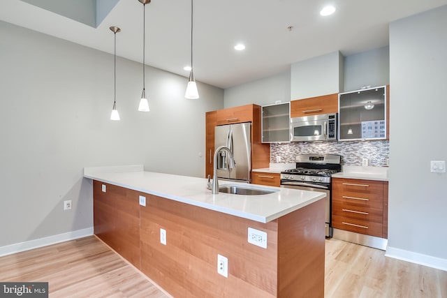 kitchen with decorative backsplash, a peninsula, brown cabinets, and appliances with stainless steel finishes