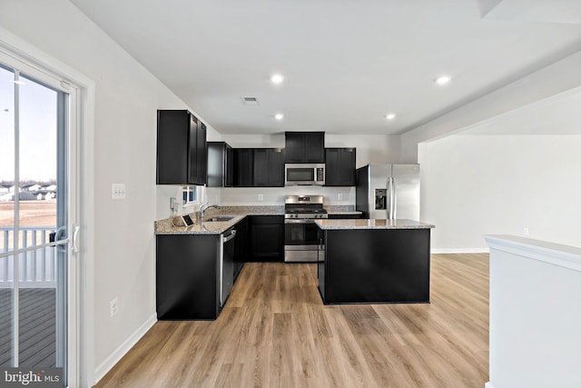 kitchen with light stone countertops, appliances with stainless steel finishes, dark cabinetry, and a healthy amount of sunlight