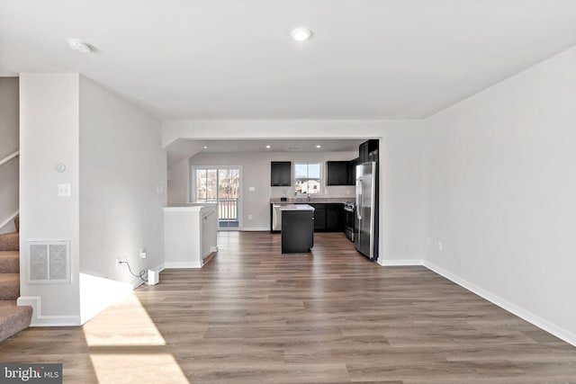 unfurnished living room with visible vents, recessed lighting, stairway, and wood finished floors