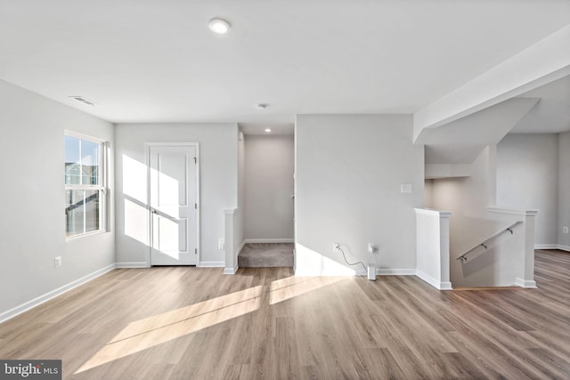 unfurnished living room with wood finished floors, visible vents, and baseboards