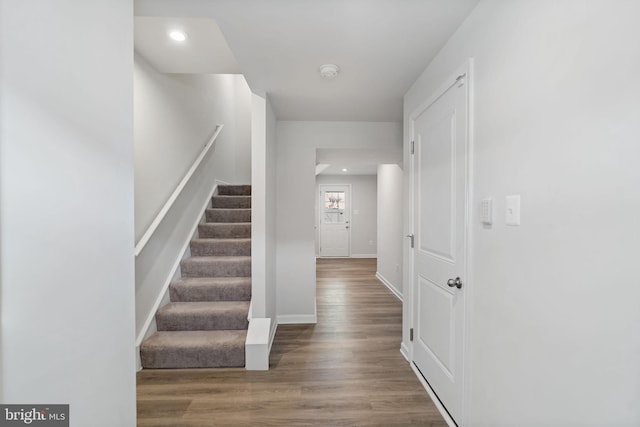 corridor with recessed lighting, stairway, baseboards, and wood finished floors