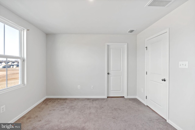 carpeted spare room featuring visible vents and baseboards