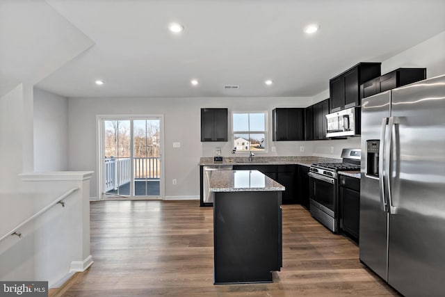 kitchen with stainless steel appliances, dark wood finished floors, dark cabinetry, and a center island